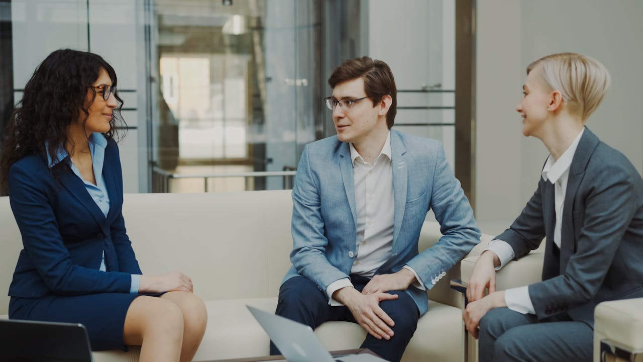 Three professionals in a business meeting, discussing ideas in a modern office environment.